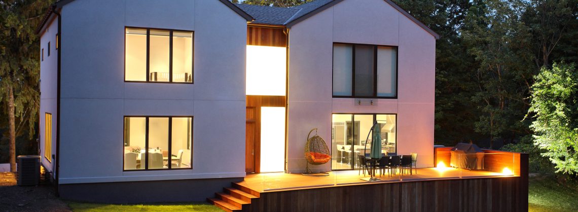 Ein Bild von einem modernen Luxushaus und Garten in der Dämmerung, das weiße Haus ist innen beleuchtet