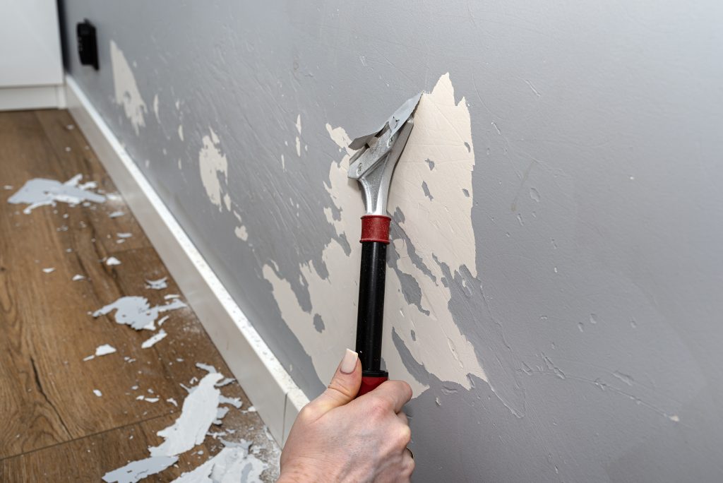 Auf dem Bild ist eine hellblaue Wand, die mit einem Spachtel abgekratzt werden.
