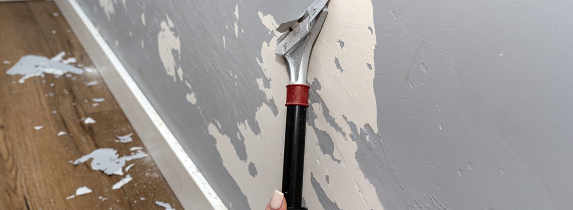 Auf dem Bild ist eine hellblaue Wand, die mit einem Spachtel abgekratzt werden.