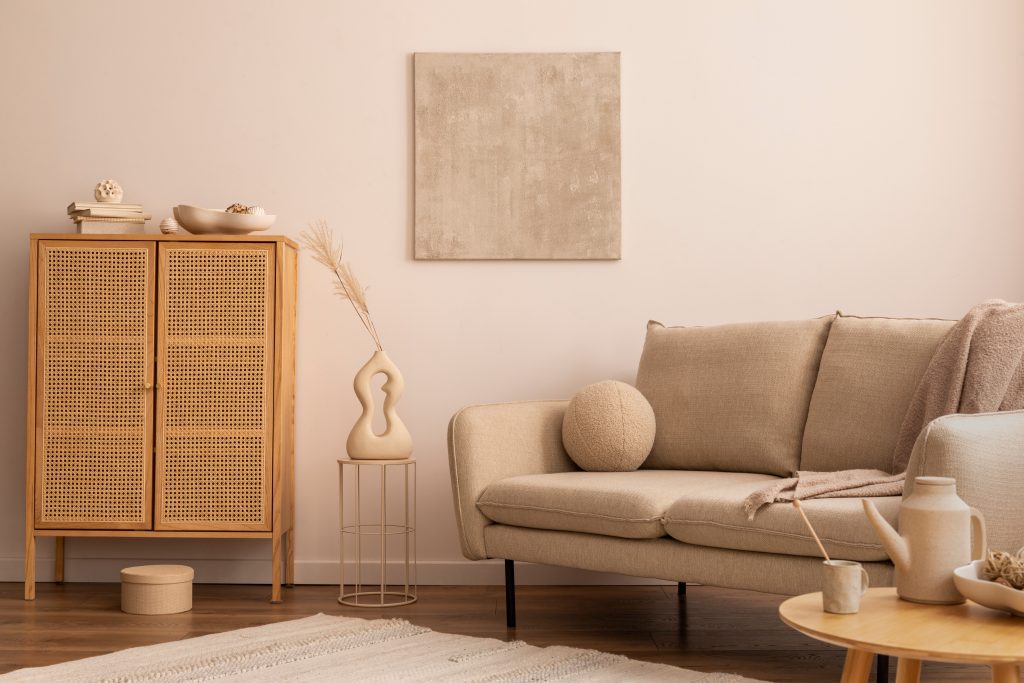 Wohnzimmer in Beigetönen mit einem Holzschrank und einem beigen Sofa mit einem kleinen Holz Beistelltisch.
