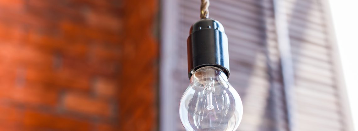 Glühlampe auf orangefarbenem Backsteinmauerhintergrund.