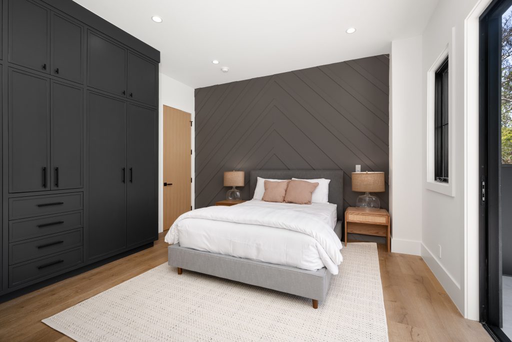 So wird das Schlafzimmer im Eigenheim zum Wohntraum 1 Modernes Schlafzimmer mit dunklen Einbauschränken, einem gemütlichen Bett und hölzernen Beistelltischen, einer Akzentwand mit Chevronmuster und Tageslicht.