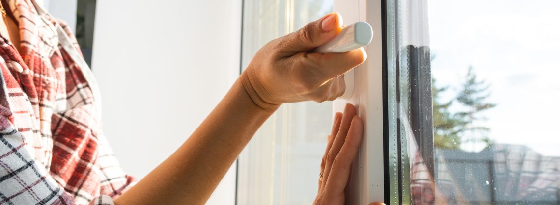 Die Hand hält den Griff eines doppelt verglasten Kunststofffensters und schließt und öffnet das Fenster