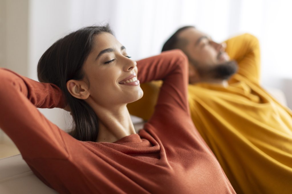 Entspannungskonzept. Glückliches, entspanntes junges Paar, das sich zu Hause auf dem Sofa zurücklehnt