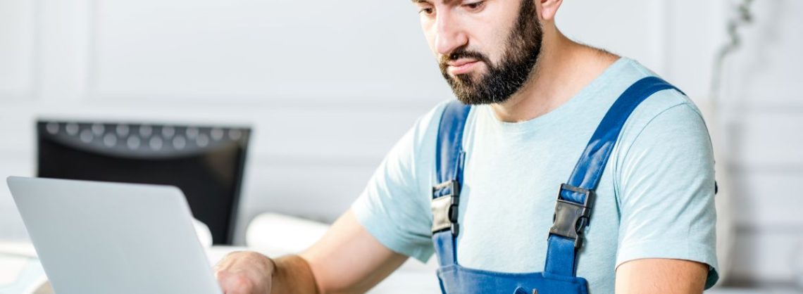 Handwerker schreibt Rechnung am Laptop