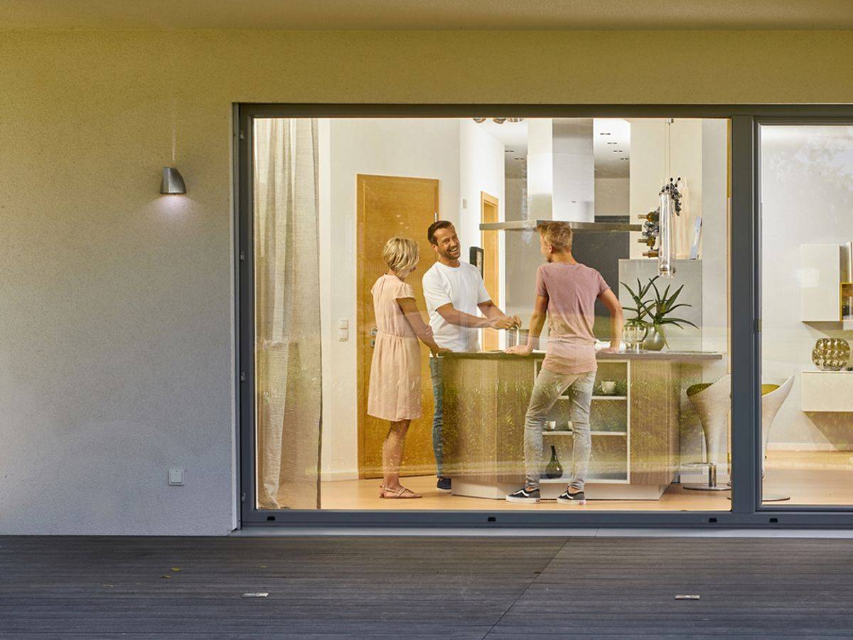 Haus von außen mit großem Fenster und Freunden beim Kochen