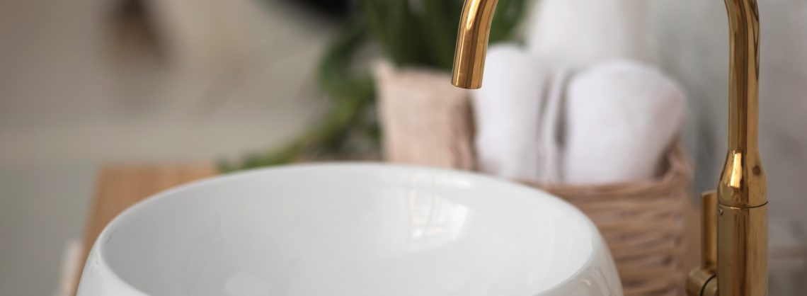 Sanitär: Weißes Waschbecken und goldene Armatur
