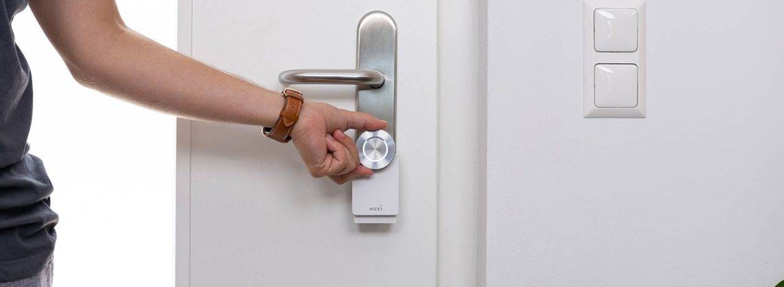Nuki Smart Lock an einer Tür, dargestellt mit Hand am Lock.
