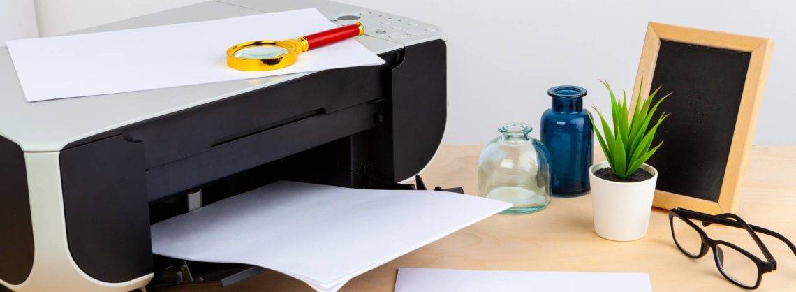 Drucker mit Papier, Brille, diversen Vasen und kleiner Tafel.