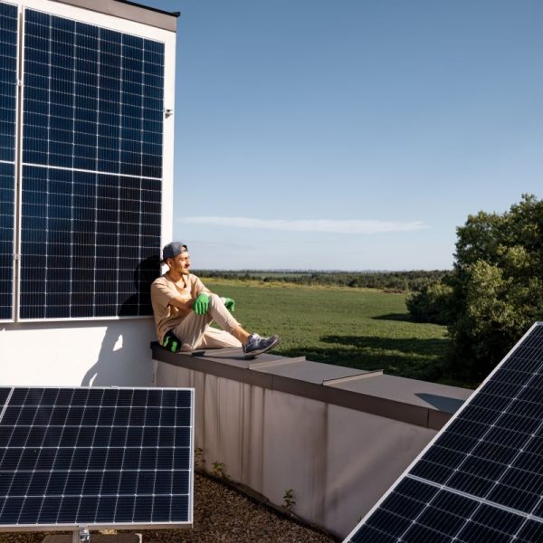 Solaranlagen auf einem Balkon, ein Mann sitzt auf der Brüstung seines Balkons.