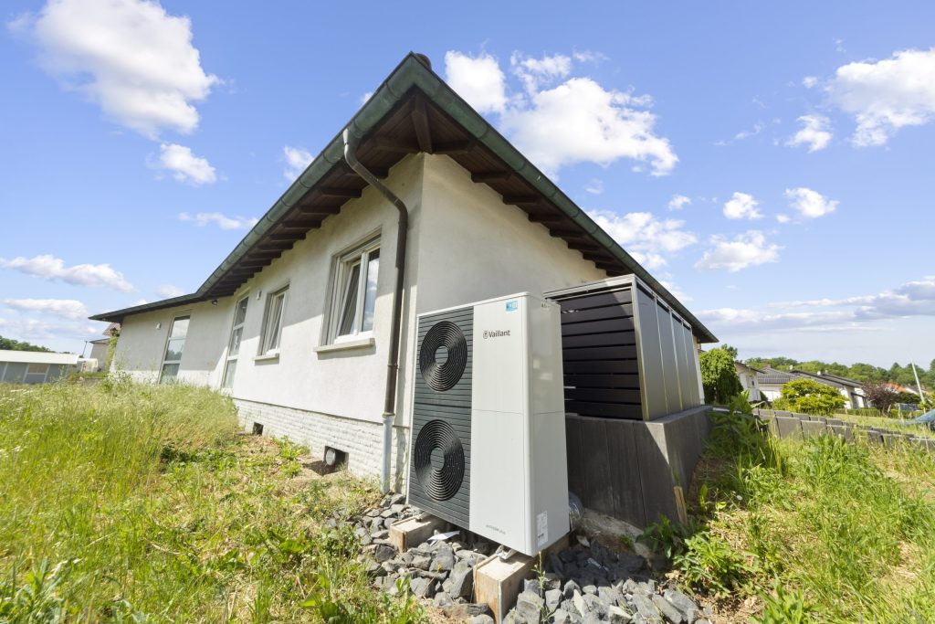 Deckenheizung: Sanieren für die Zukunft 4 Vor einem einstöckigen Bungalow steht eine Wärmepumpe.